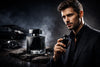 Elegant man in black suit holding luxury men's perfume bottle, dark upscale background